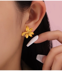 Close-up of a 3D gold flower stud earring with five petals on a model's ear