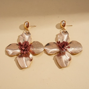 Detail of vintage gold flower earrings with brushed texture and deep red pistils