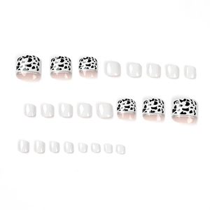 Press-on toenails featuring black cow print French tips and glossy white solid finish