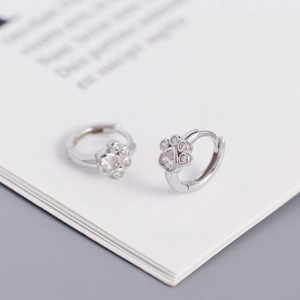 Macro shot of silver S925 paw print earrings with sparkling heart-shaped zircon detail