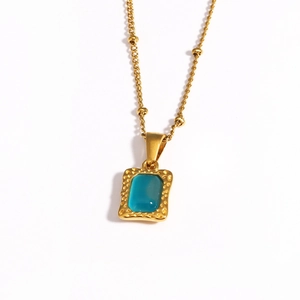 Detail van een vintage gouden ketting met rechthoekige blauwe edelsteen en gehamerde textuur