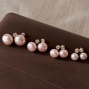 Macro shot of four sizes of pink pearl earrings with S925 silver needles on a dark background