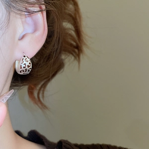 Vue macro de boucles d'oreilles argentées en C avec des détails émaillés motif léopard rétro