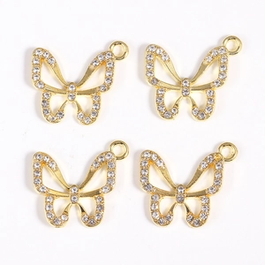 Detailed macro view of four golden alloy butterfly charms with inlaid white rhinestones