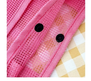 Detail of pink mesh travel bag showing reinforced webbing and black snap fasteners
