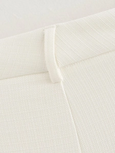 Detail of white fabric waistband showing stitching and belt loop on wide-leg trousers