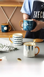 Detail of ceramic mugs featuring hammer textures, wooden lids, and gold stirring spoons