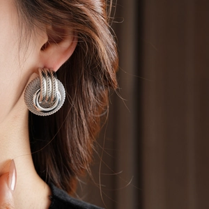 Close-up of interlocking silver circular hoop earrings with mesh texture on model