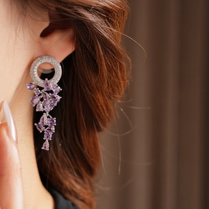 Dettaglio di orecchini di cristallo viola con perno rotondo su una modella per un look elegante