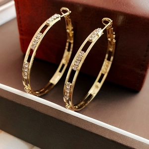 Detail of gold geometric hoop earrings with sparkling rhinestones on leather background