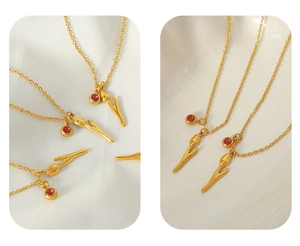 Detail of 18k gold plated tulip necklace featuring a red rhinestone on satin fabric