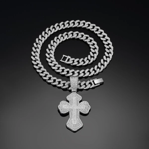 Macro detail of iced-out silver cross pendant with cuban chain on black background
