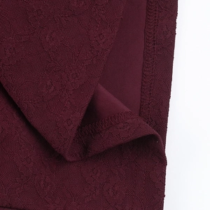 Macro-opname van donkerrode kantstof met fijne mesh-details en precieze stiksels