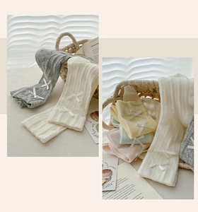 Detail of knit socks with white bows in grey, cream, yellow, green and pink colors