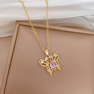 Detail view of a gold hollow butterfly pendant with pink stone and small clear gems