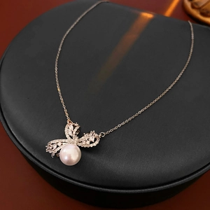 Détail du pendentif nœud serti de zircons avec perle blanche sur chaîne en argent