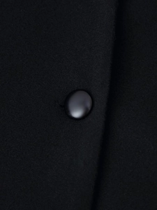Gros plan sur la texture du manteau en laine noire avec un bouton lisse assorti