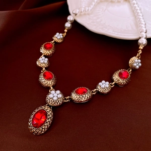 Detailed macro of vintage necklace with red gemstones and pearls on silk fabric