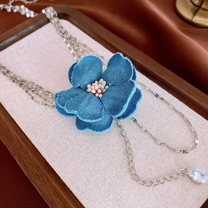 Collier multicouche avec fleur en denim bleu, chaînes argentées et pendentif en zircon