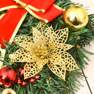 Detail of Christmas wreath with golden glitter flower, red ribbon bow and pine needles