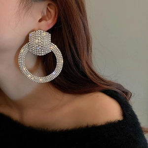 Detailed view of oversized silver hoop earrings with shimmering rhinestones on model