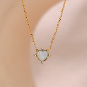 Detail of gold heart pendant with iridescent opal and sparkling diamond accents