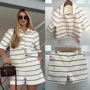 Detail of striped knit set showing textured fabric and metallic buttons on a white top