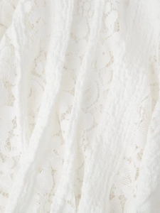 Gros plan détaillé de la texture de dentelle blanche et des motifs floraux sur la robe