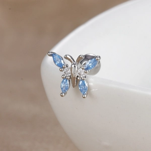 Gros plan d'un piercing hélix papillon serti de zircons bleus en forme de marquise