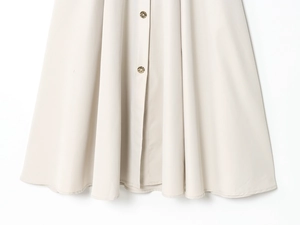 Close-up of light beige dress fabric featuring two decorative gold metal buttons