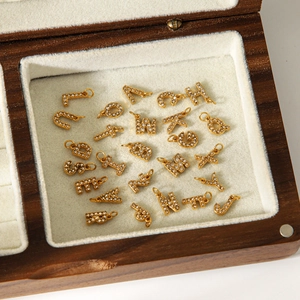 Pendentifs alphabet en acier doré avec cristaux étincelants dans une boîte à bijoux
