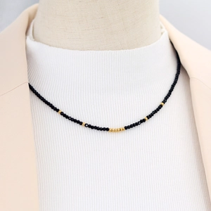Faceted black beads and gold beads beaded necklace on model in beige blazer