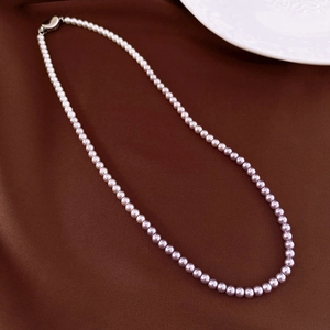 Detail of gradient pearl necklace transitioning from white to lavender on silk fabric