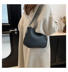 Detail of the black leather crescent shoulder bag featuring a sleek curved design and long strap