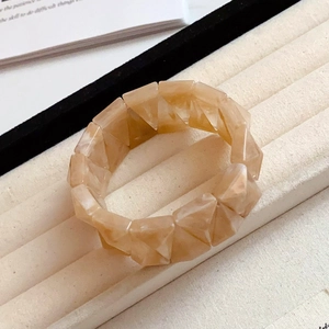 Detailed close-up of amber marble acrylic triangular link bracelet on velvet display