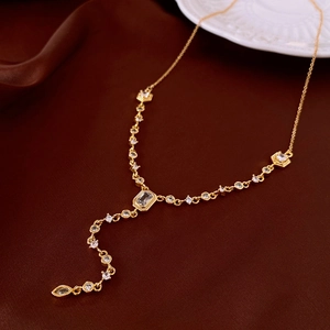 Detail of gold Y-shaped necklace featuring cubic zirconia charms on silk fabric