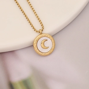 Detail of gold necklace featuring round shell pendant with moon design on a box chain