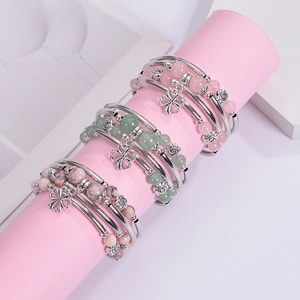 Detailed shot of layered pink zebra stone bead bracelets with clover and flower charms