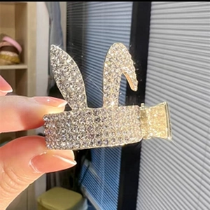 Detail of a rabbit-shaped hair claw clip in gold metal with sparkling rhinestones