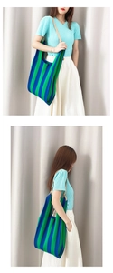 Detail of blue and green striped knit tote bag showing soft texture and slim shoulder straps