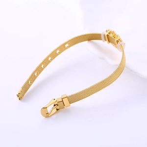 Close-up of golden mesh watch-style bracelet featuring a tree of life tree charm detail