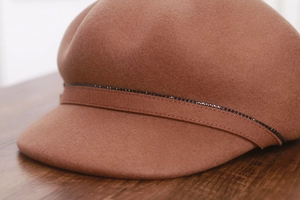 Close-up of brown wool newsboy cap featuring elegant black rhinestone trim on the brim