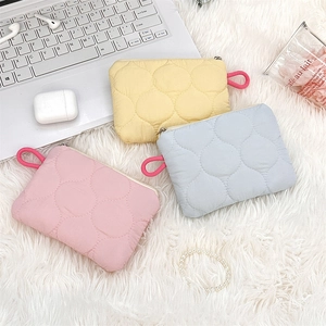 Flat lay of quilted storage pouches in yellow, pink and blue on a soft white carpet