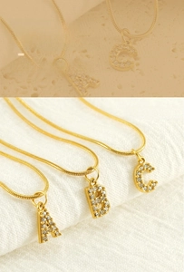 Macro detail of gold initial necklace with rhinestones and sleek snake chain