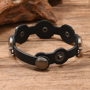 Close-up of vintage black leather bracelet featuring metal skull studs and snap closure