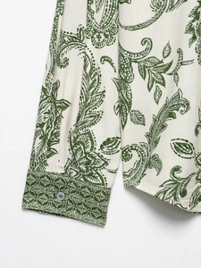 Detail of green paisley print shirt cuff with textured fabric and grey button