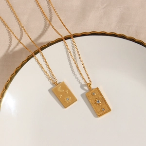 Detailed close-up of golden sun and moon tarot rectangular pendants on a white porcelain plate