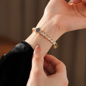 Dettaglio del bracciale dorato con occhio greco e zirconi con taglio a baguette