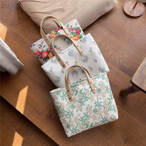 Close-up of three quilted floral cotton tote bags with leather handles and metal rivets