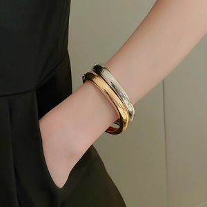 Detailed view of polished thick round metal bracelets in glossy gold and silver finishes